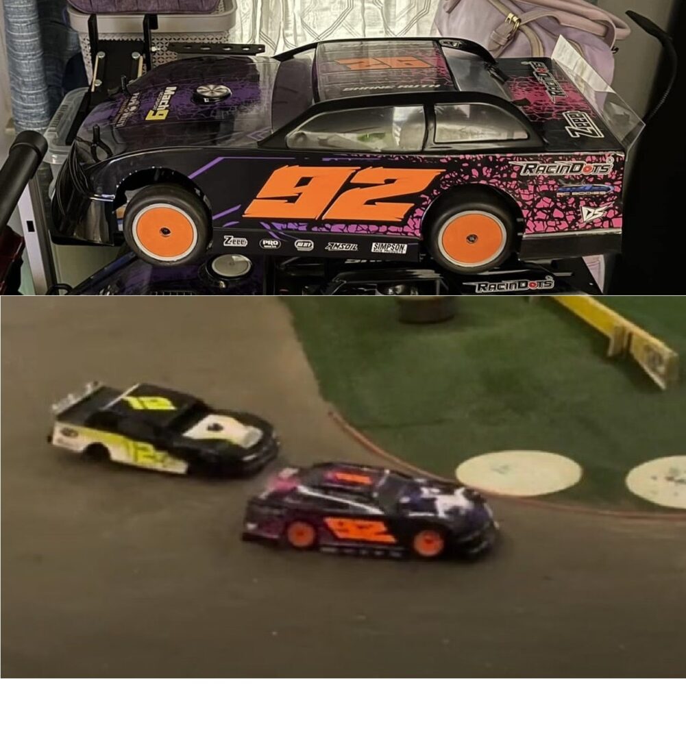 Three detailed model race cars displayed indoors, two on a track and one on a table.