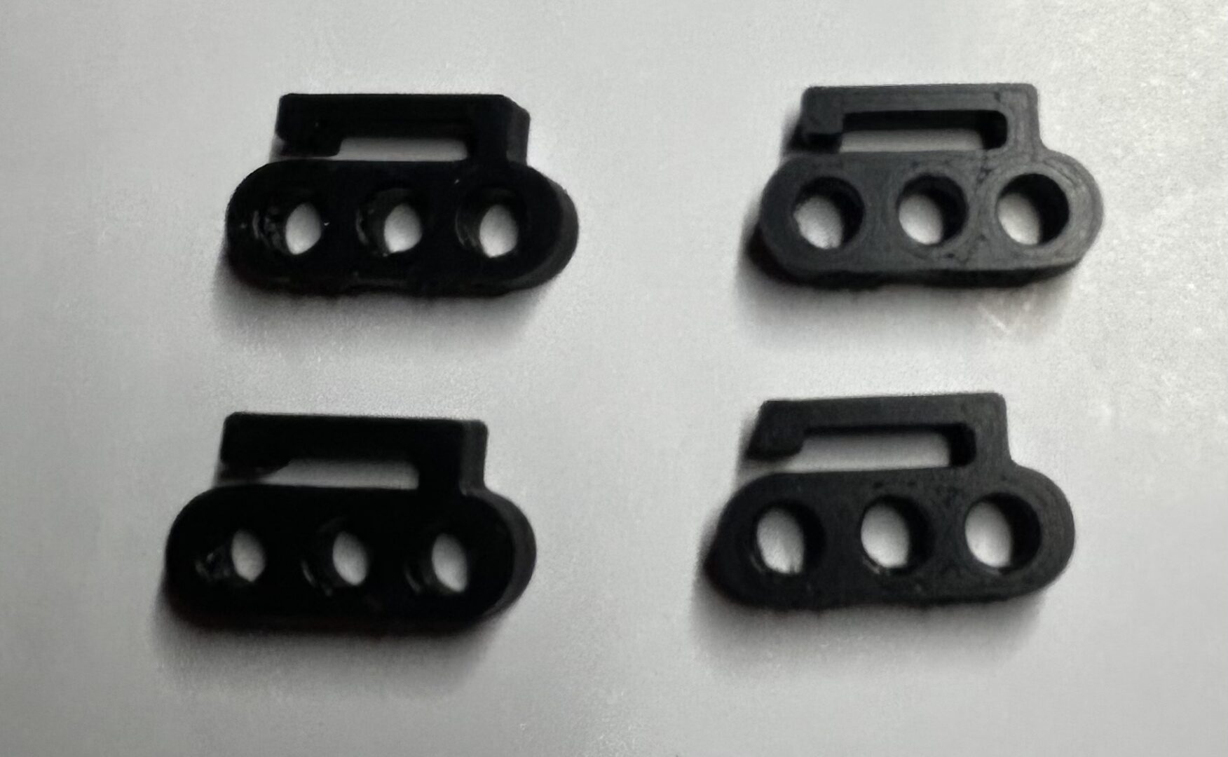 four black triple-hole plastic mounting clips