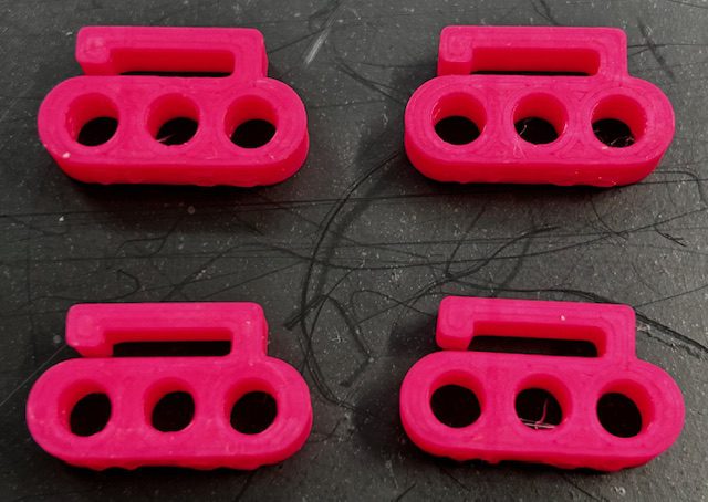 Four pink three-hole plastic cord clips
