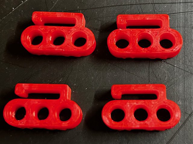 Four red plastic three-hole connectors