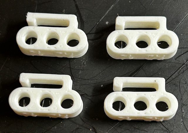 Four white three-hole plastic connectors